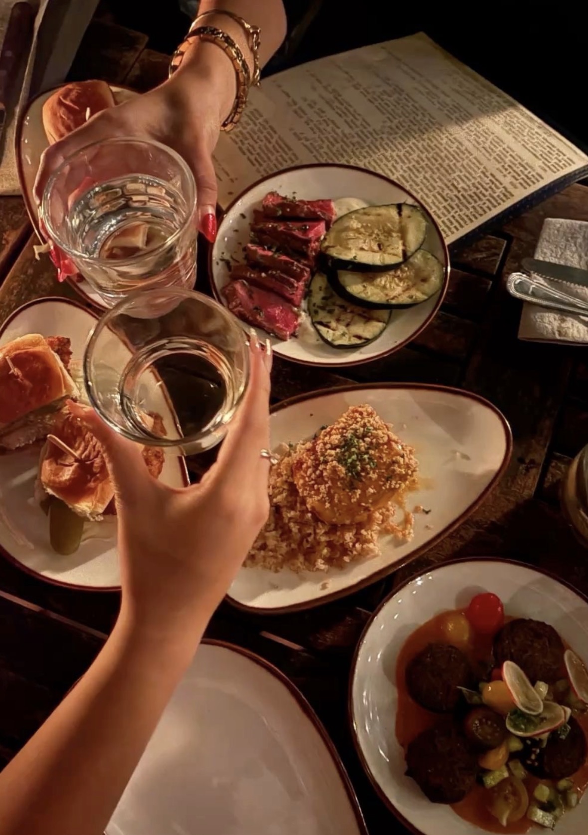Guests toasting with glasses over shared plates at a Rise Up Collective dinner